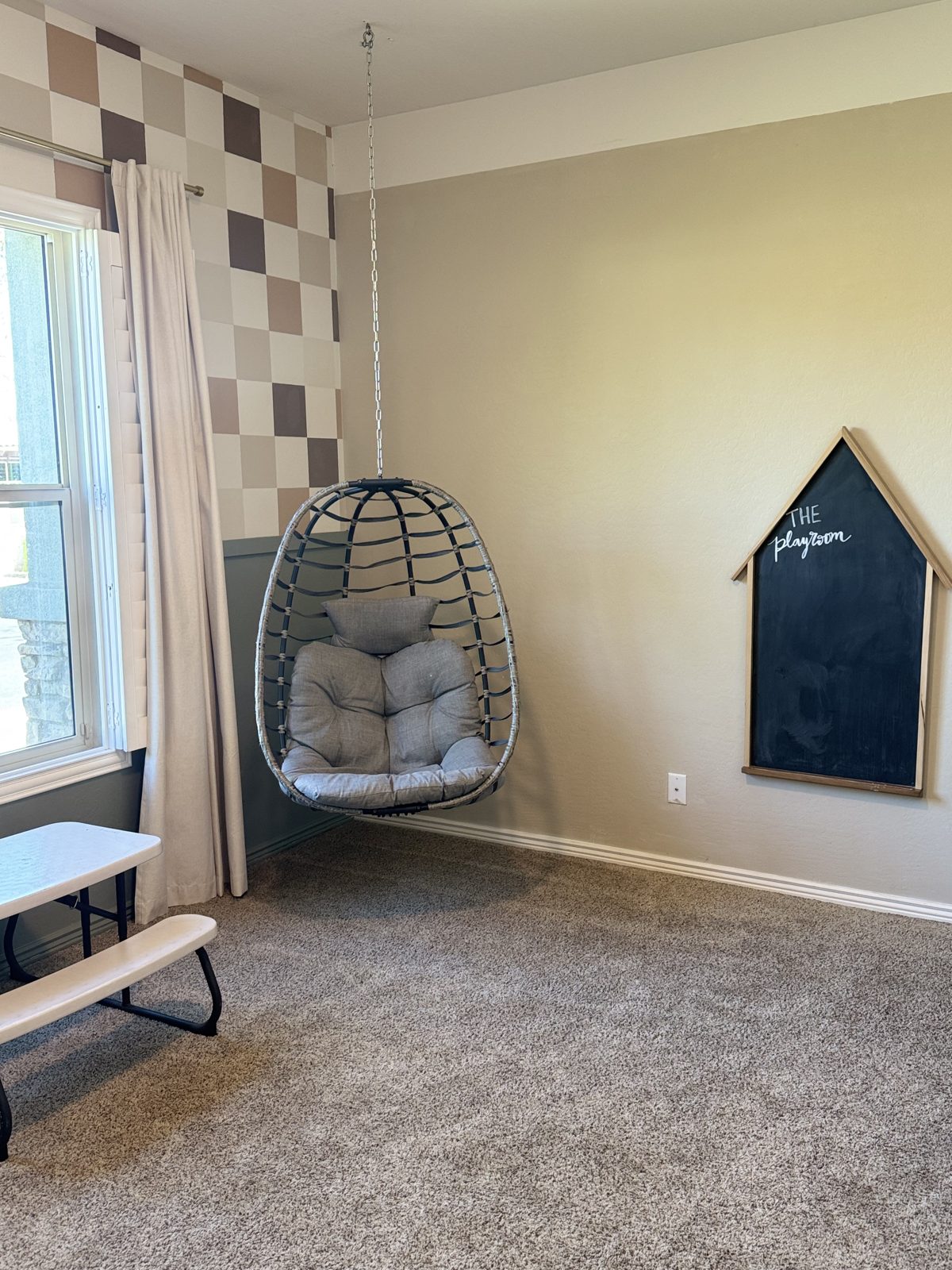 Hanging egg swing chair and house-shaped chalkboard in a playroom