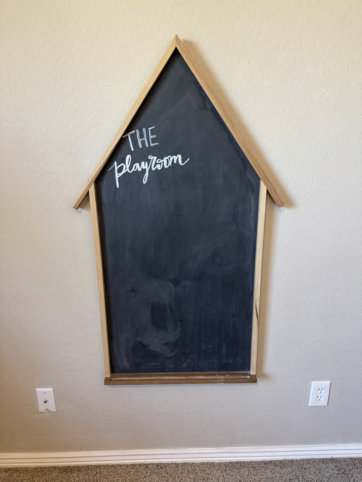 House-shaped chalkboard with the playroom written on it